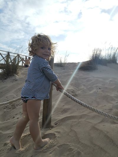 Full length of girl on sand at beach against sky