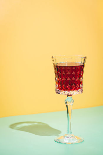 Close-up of wine glass on table against yellow background
