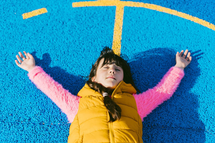 Girl relaxing with arms raised on basketball court