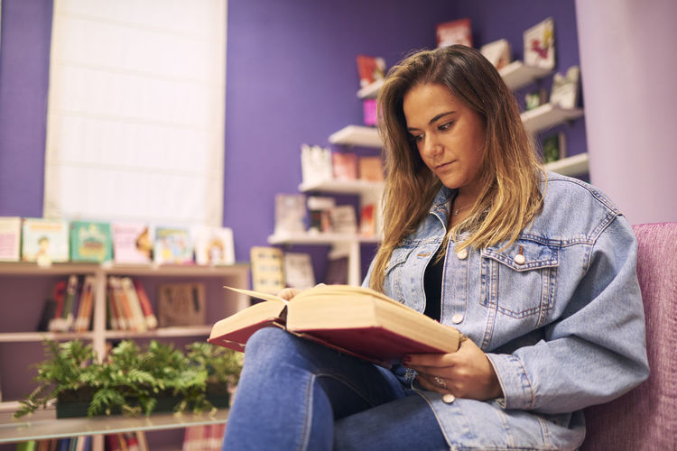 Young woman looking away while sitting on book