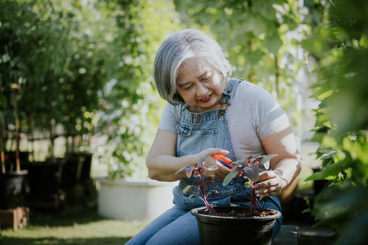 Portrait of smiling young woman gardening in park