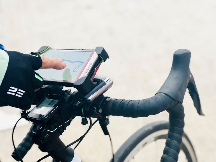 Cropped hand of person using mobile phone on bicycle