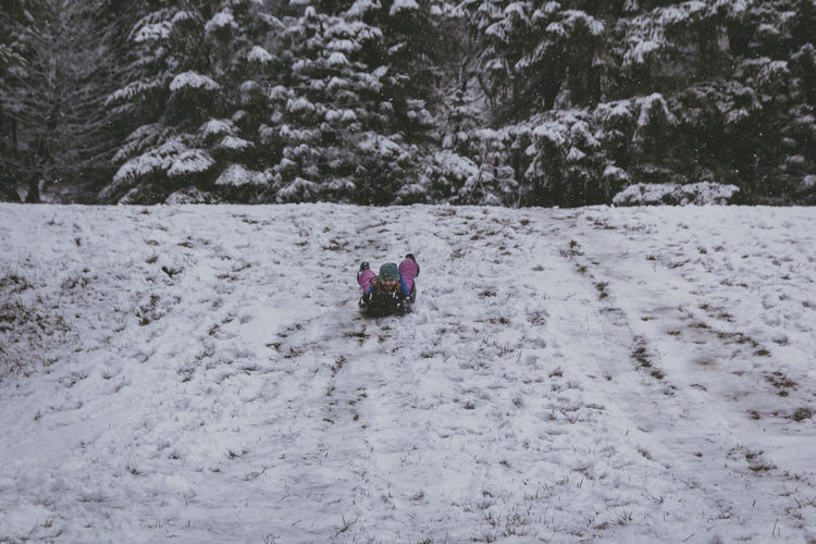 Full length of girl sitting on bobsled in snow