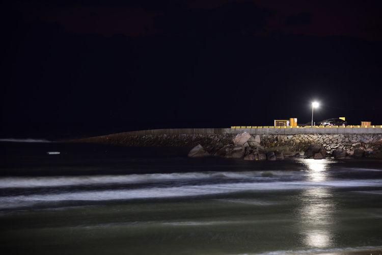 Illuminated sea against sky at night