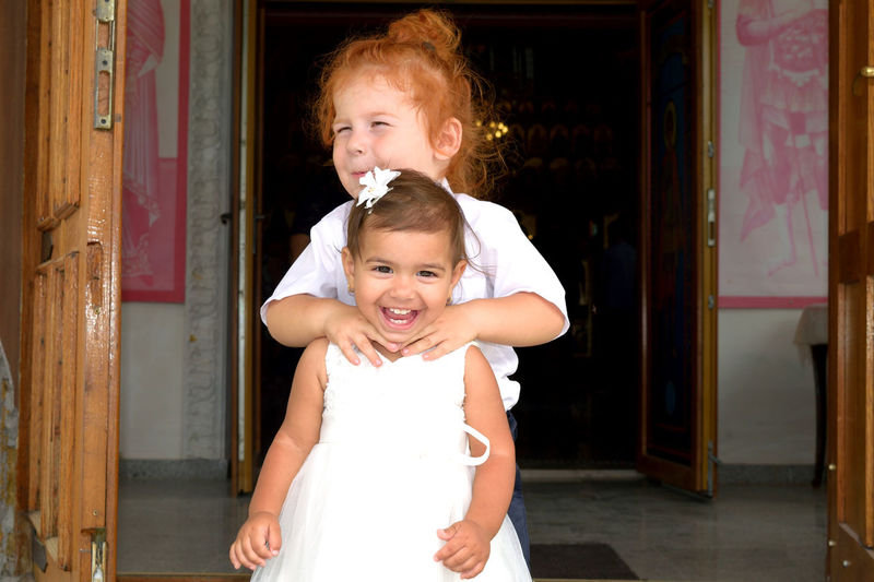Cute boy strangling sister neck while standing at entrance
