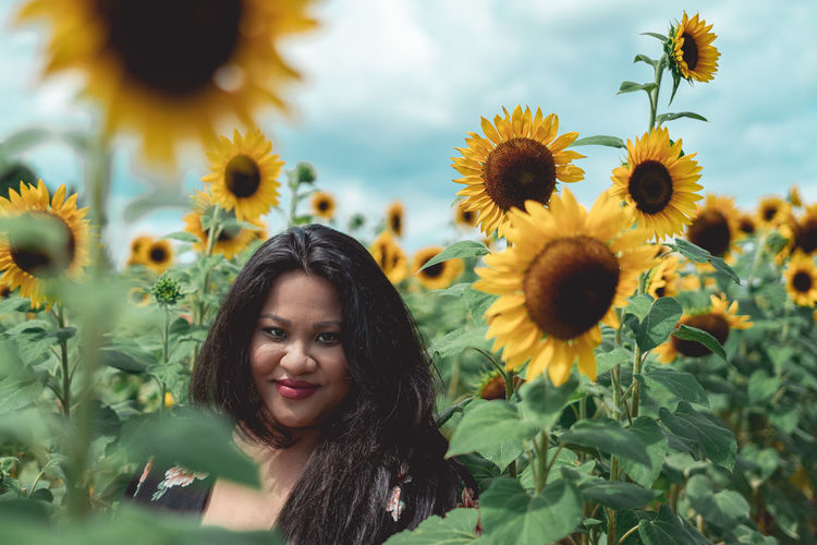 Portrait of smiling woman against sunflower