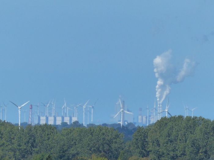 Wind turbines in factory against blue sky