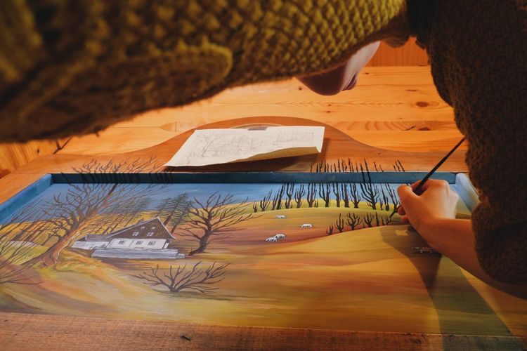 Low angle view of woman drawing on canvas in cottage
