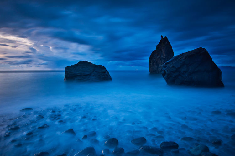 Rocks in sea against blue sky
