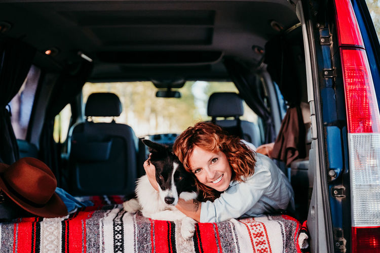 Portrait of woman with dog lying in camper trailer