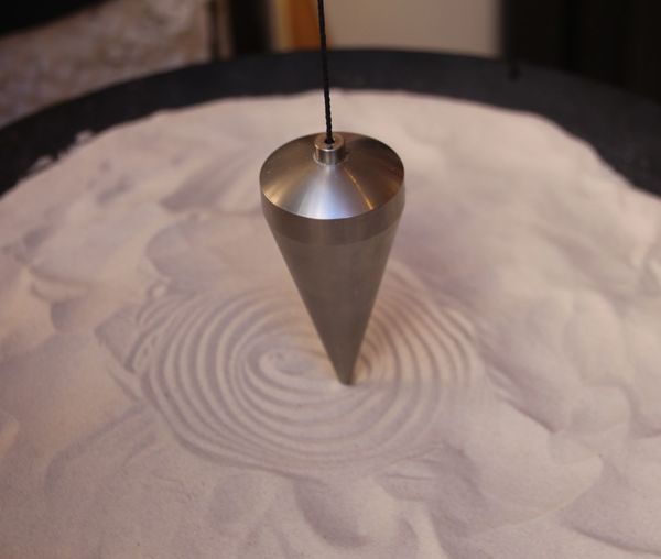 Close-up of pendulum hanging over sand
