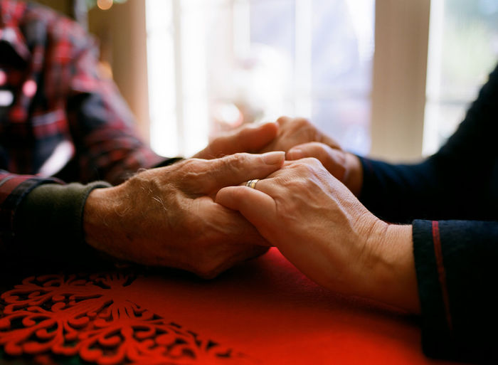 Father holding daughter's aged hands. comforting warming old age