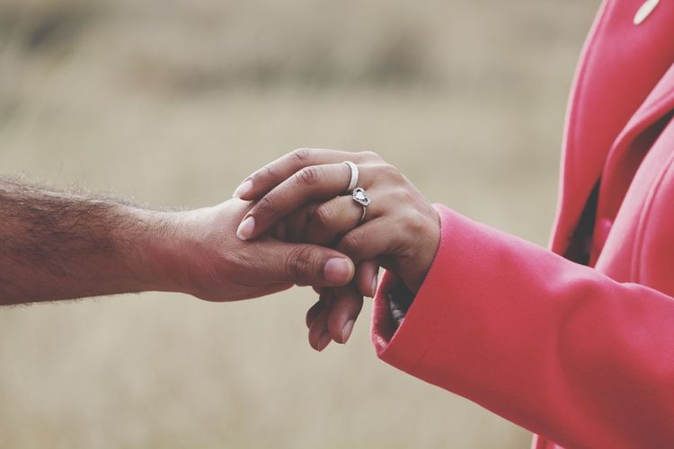 Cropped image of people holding hands outdoors