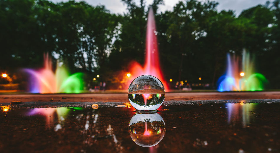 Close-up of crystal ball on water against trees at night