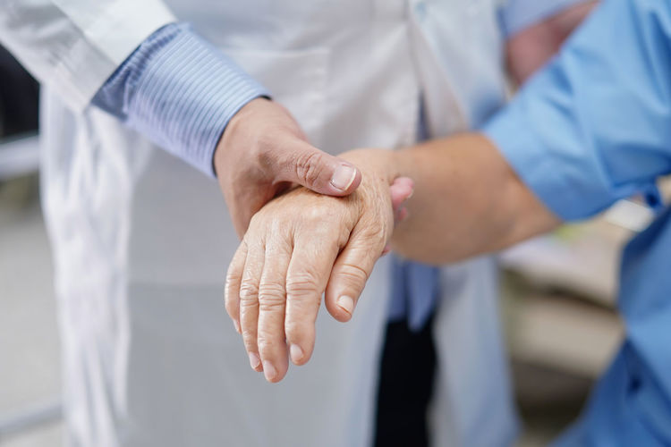 Midsection of doctor holding patient hands
