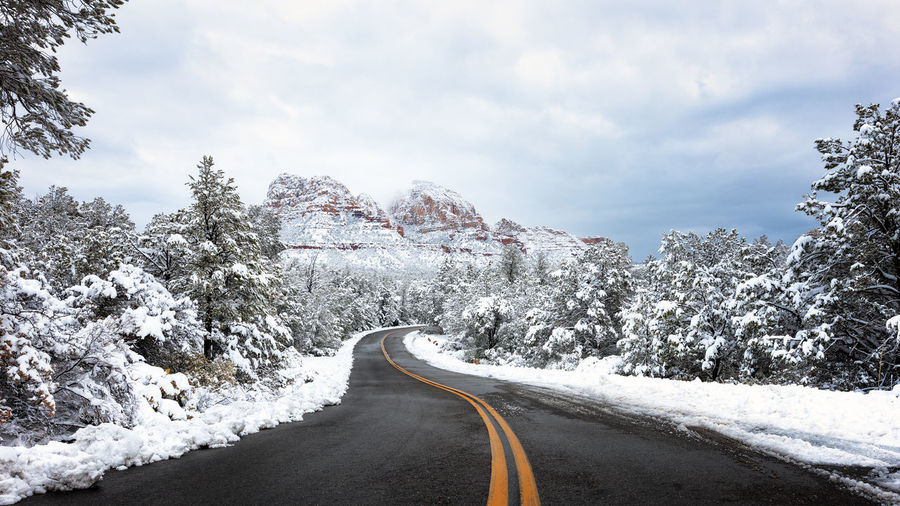 Winding road through a scenic red rock landscape with snow in sedona, arizona.