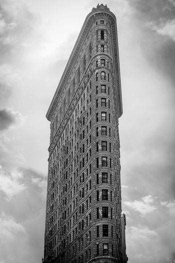 Low angle view of flatiron building against cloudy sky