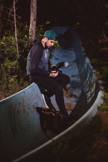 Photographer holding camera while sitting on slide at night