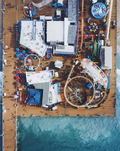 Aerial view of people at amusement park on pier over sea