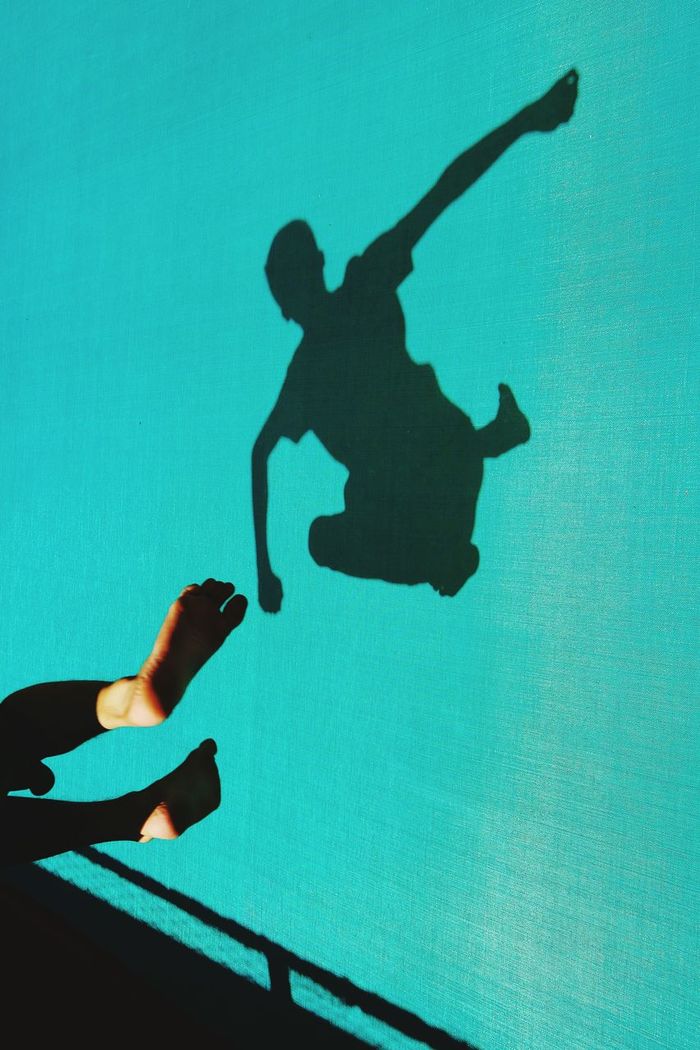 Shadow of man in swimming pool while jumping