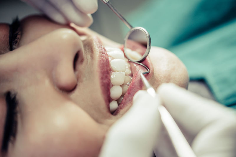 Close-up of young woman getting her teeth examined by dentist