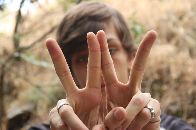 Close-up portrait of man showing peace sign