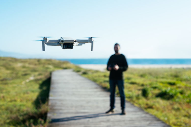 Young man flying a dron near to the beach