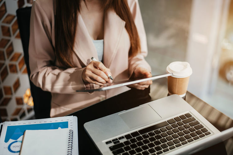 Midsection of businesswoman using laptop at office