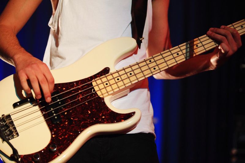 Midsection of musician playing bass guitar in concert