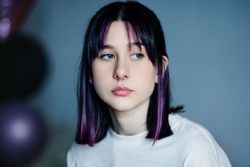 Portrait of a pensive young girl with purple hair and a nose ring