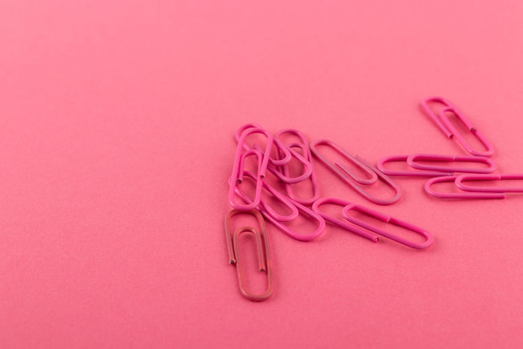 High angle view of paper clips on pink background