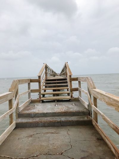 Wooden pier on beach against sky