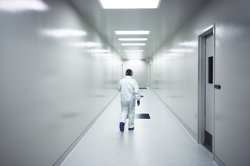 Rear view of scientist walking in corridor  person