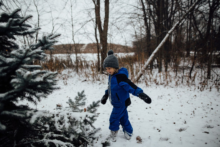 Little boy in snowsuit playing in snow during the winter