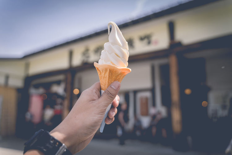 Ice cream in the hand held up in the sky in vintage tone.