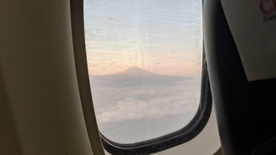 Airplane flying in sky seen through glass window