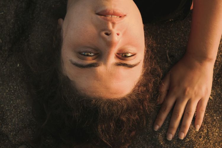High angle portrait of young woman lying on field