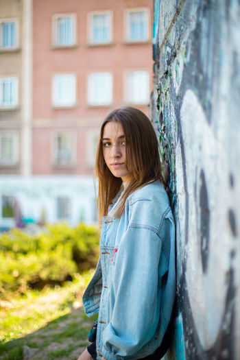 Portrait of teenage girl standing against graffiti wall