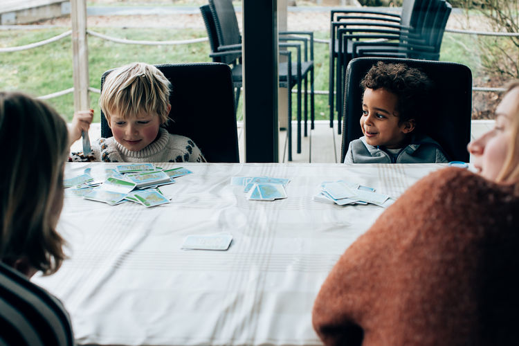 Family moment. sisters at home with their children play a game at the table. multiracial friends