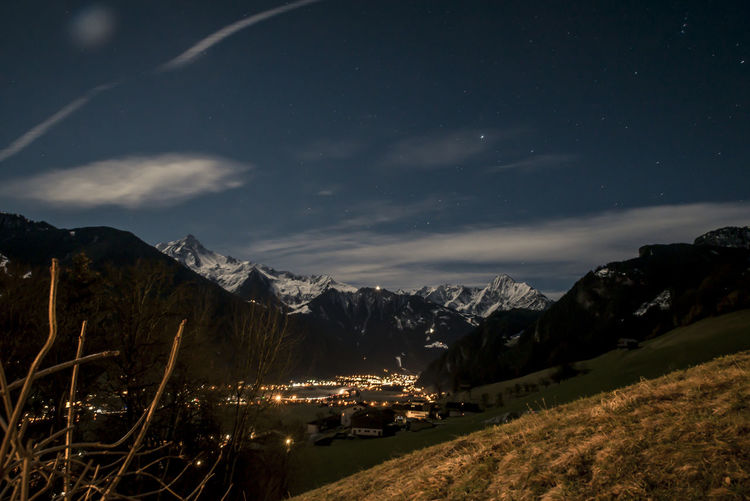 High angle view of illuminated houses amidst snow capped mountain against sky at night