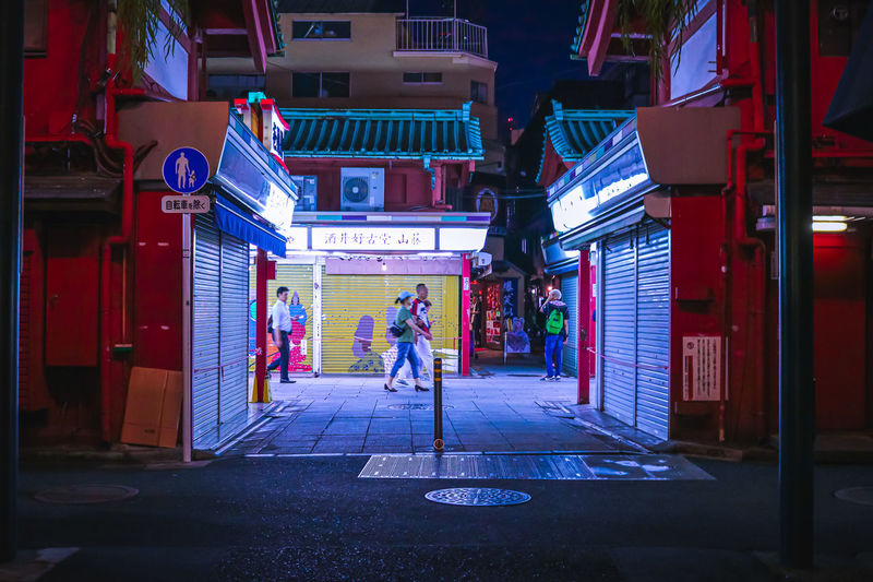 People walking on street amidst buildings at night
