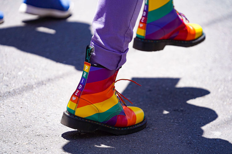 Low section of man walking with rainbow colored shoes on road