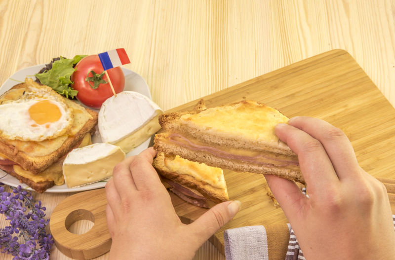 Woman holding croque monsieur sandwich slice