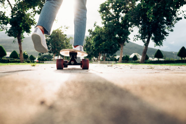 Low section of man skateboarding on footpath at park