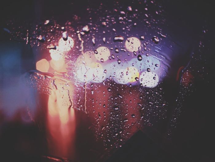 Close-up of raindrops on glass window at night