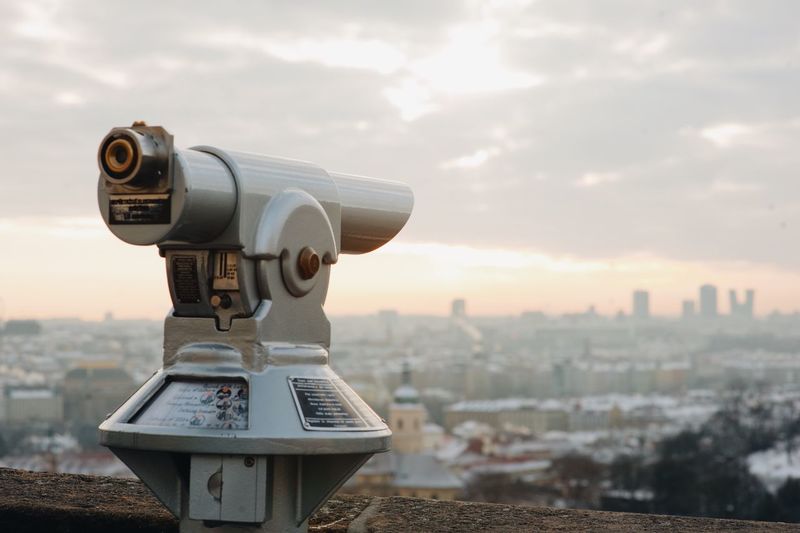 Close-up of hand-held telescope against cityscape during sunset