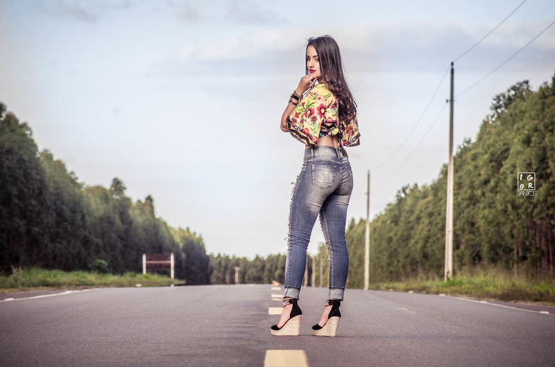 Full length of woman standing on road against sky