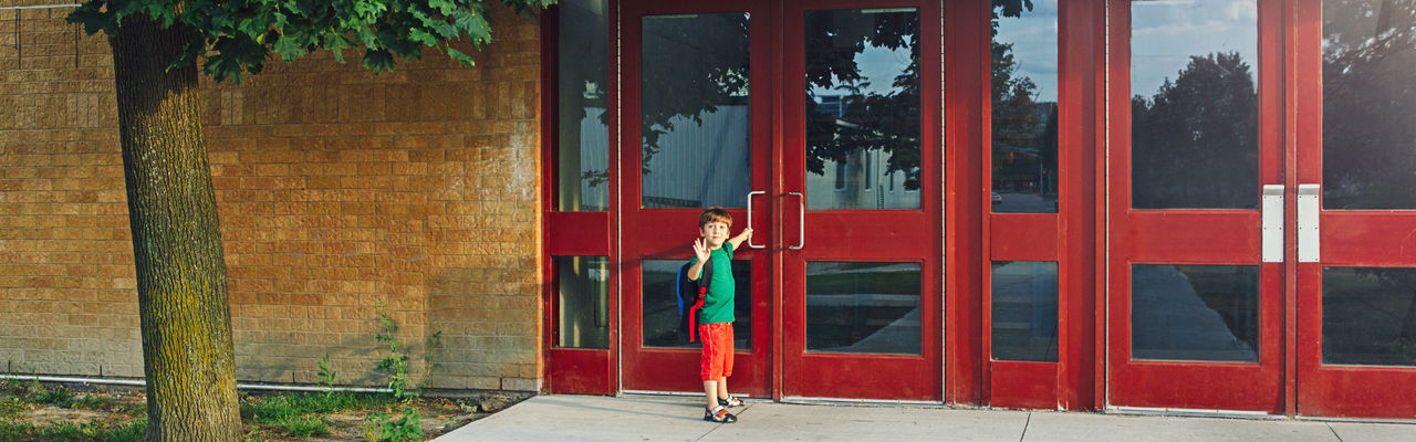 Full length of boy with backpack standing by door
