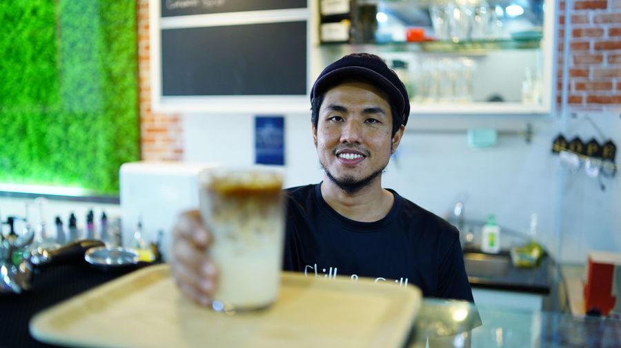 Smiling man serving drinks at cafe