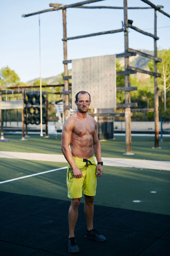 Shirtless fit young man posing at outdoors gym military camp